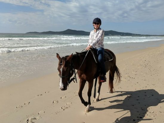 lady on beach horse riding, illustrating she's wearing a comfortable bra for exercise, in the post best bras for women over 50