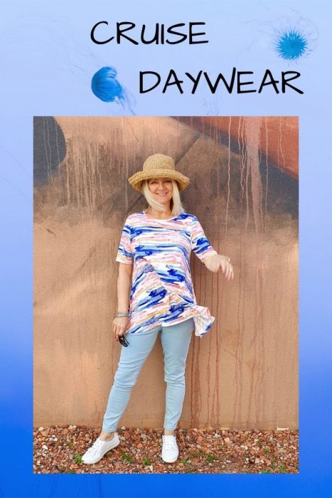 Woman in straw hat, stipey top, blue jeans and white sneakers showing what to wear on a cruise