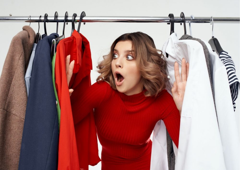 woman looking through clothes on a rail. Blog Post How to Look Stylish Everyday on a Budget.