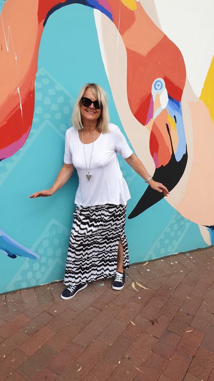 Blond woman wearing white T, and long black and white skirt.