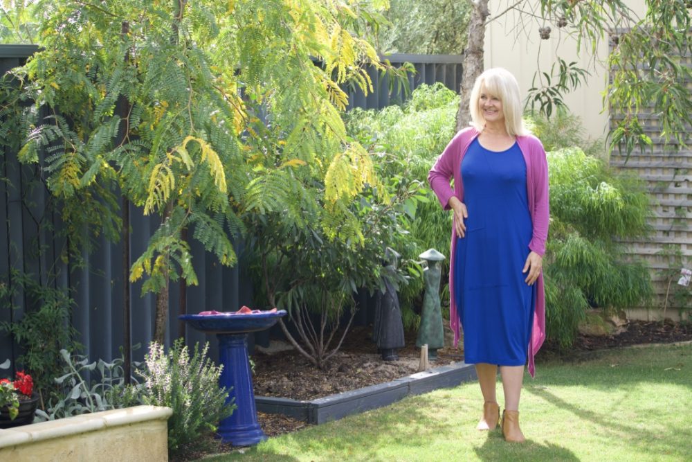 Woman wearing a blue dress and a lilac cardigan illustrating a point in the blog post about the best dresses for women over 50