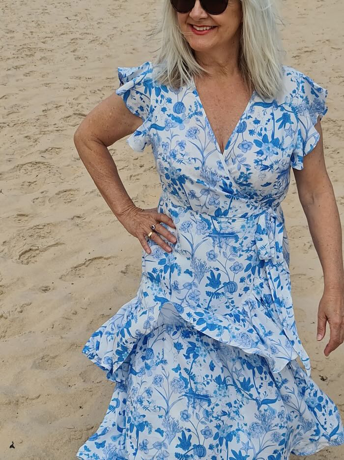 Woman wearing a blue floaty dress by the seaside.