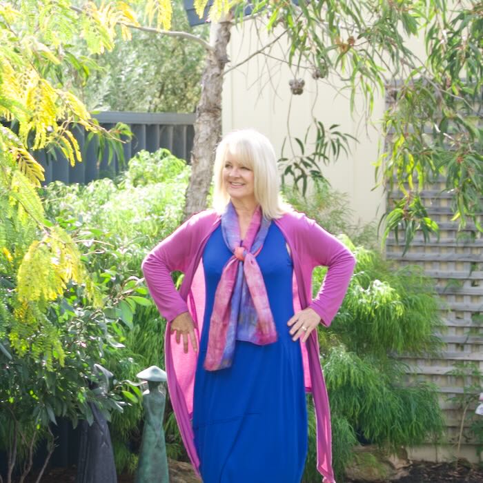 Blond women wearing bright blue dress and lilac cardigan illustrating dress styles to suit women with pear shaped bodies.