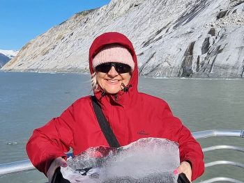 Sailing with Princess Cruises Alaska. Woman in red jacket holding a large chunk of glacial ice.