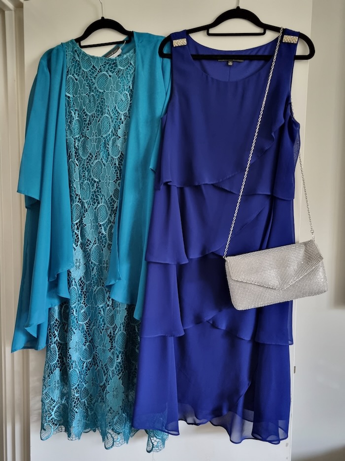 Two dresses in jewel colors suitable as formal wear outfits. One is in a turqoise blue, the other is in a saphire blue. There is a silver handbag in the image too.