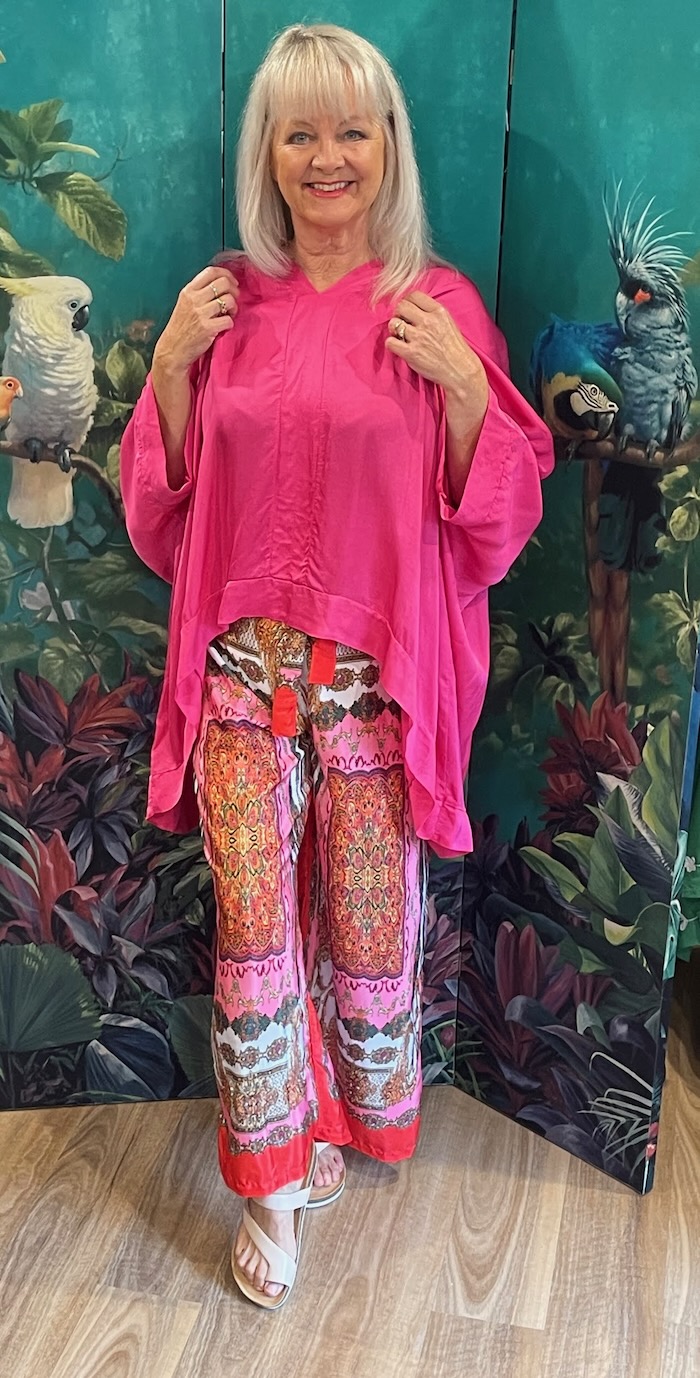 Woman wearing a dress to impress outfit consisting of a silky pink top and arty wide leg trousers.