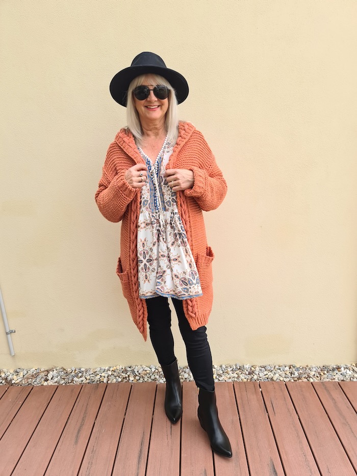 Model illustrating what to wear if you're short and curvy. Boho blouse, long rust colored cardigan, black pants and boots.