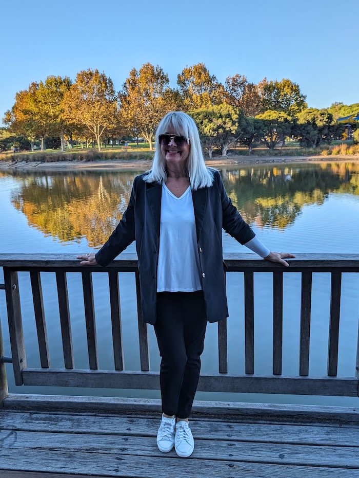 Woman standing by a lake wearing a black and white outfit.