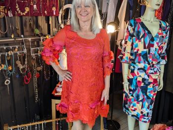 Woman in a charity shop, wearing a red recycled dress