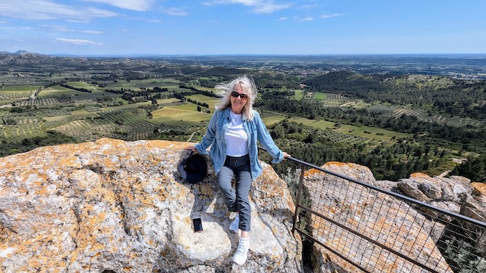 Woman sitting on a rock with a view showing an outfit illustrative of what to wear in South of France in May.