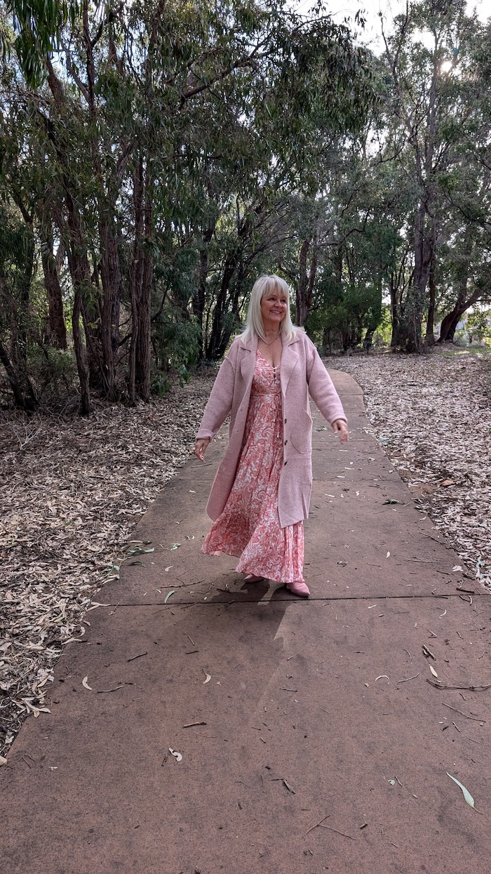 Jo Castro is walking on a forest footpath and wearing the Rachel boho style maxi dress and Davie coatigan from Salty Crush.